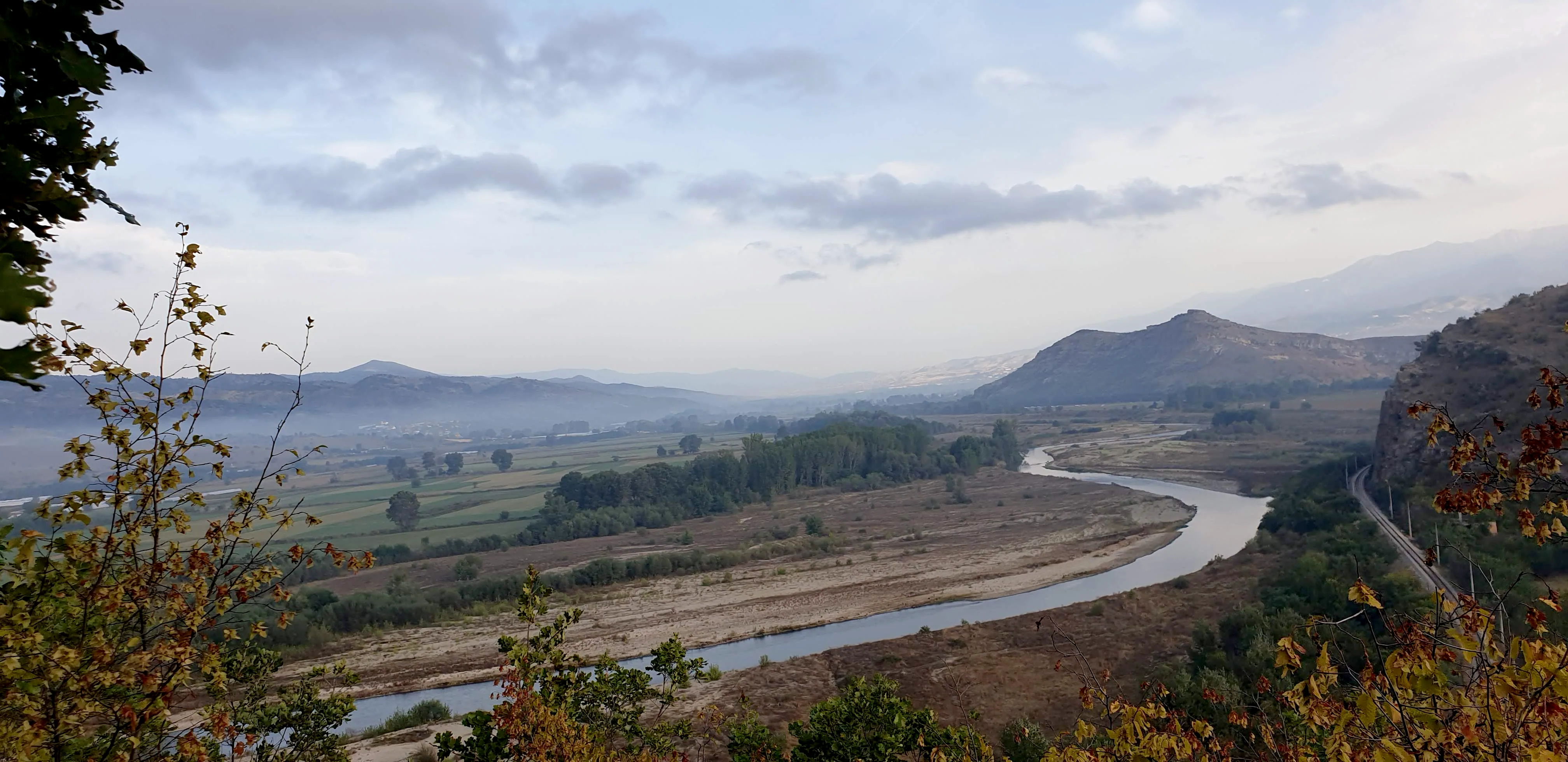 A mountain ridge above a wide river valley at dusk.